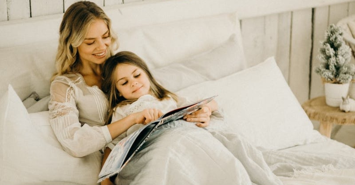 mom reading a book to daughter on sofa